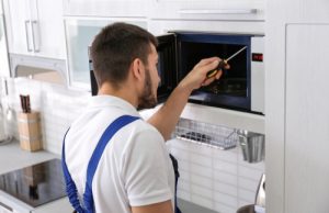 Young,man,repairing,microwave,oven,in,kitchen