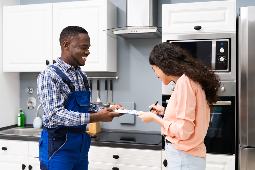 Smiling,customer,woman,signing,appliance,repair,invoice,in,front,of