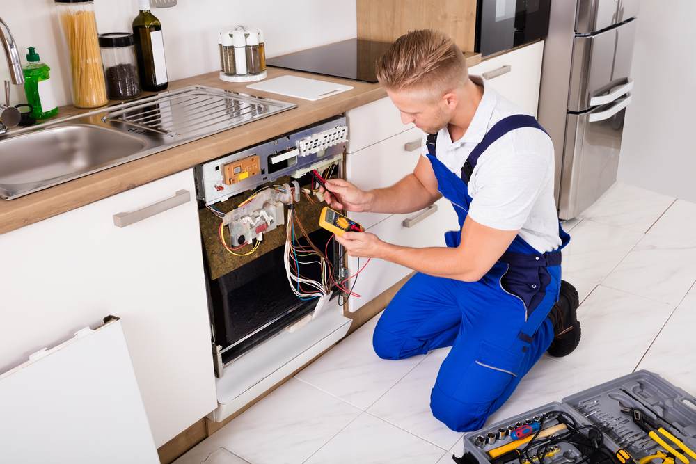 Young,repairman,checking,dishwasher,with,digital,multimeter