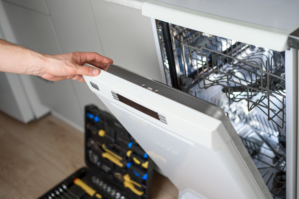 Man,repairing,a,dishwasher,with,tools