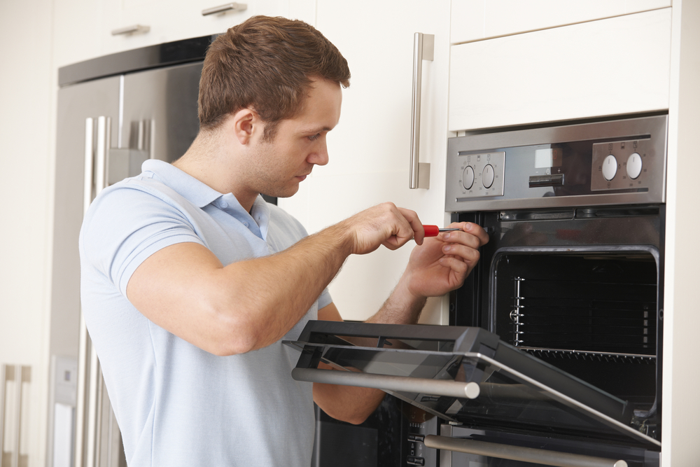 Man,repairing,domestic,oven,in,kitchen